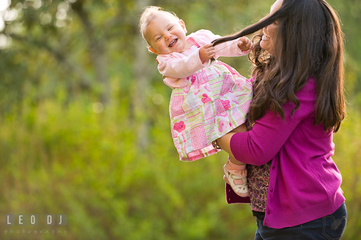 Baby girl pulling her mother's hair laughing. Washington DC, Silver Spring, Maryland candid children and family lifestyle photo session by photographers of Leo Dj Photography.