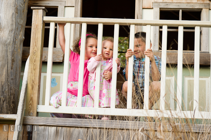 Brother and sisters peeking through a tree house fence. Washington DC, Silver Spring, Maryland candid children and family lifestyle photo session by photographers of Leo Dj Photography.