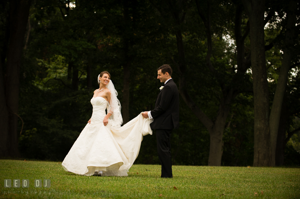 Bride walking while Groom holding her wedding gown train. Aspen Wye River Conference Centers wedding at Queenstown Maryland, by wedding photographers of Leo Dj Photography. http://leodjphoto.com