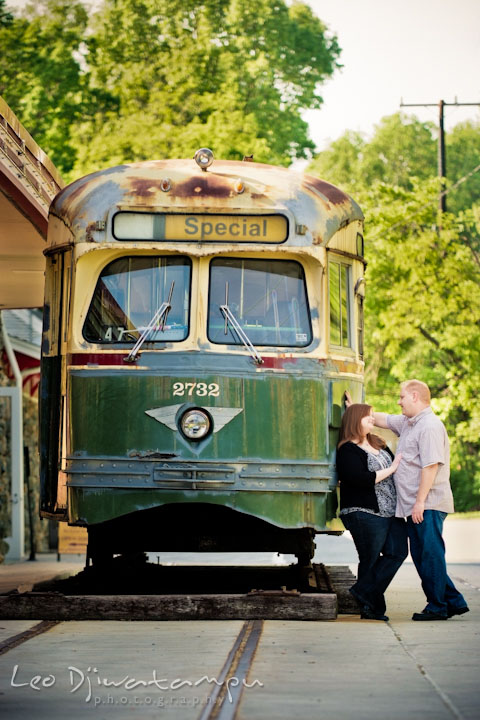 Engaged couple talking to each other by an old trolley or tram. Pre wedding engagement photo session at Glen Echo Park Maryland by wedding photographer Leo Dj Photography