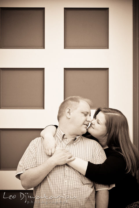 Engaged couple cuddling by an antique door. Pre wedding engagement photo session at Glen Echo Park Maryland by wedding photographer Leo Dj Photography