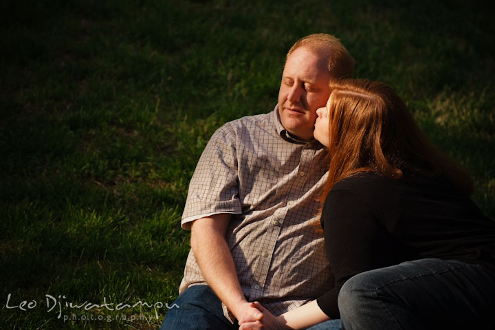 Engaged girl sitting on the ground with her fiancé and kissed him. Pre wedding engagement photo session at Glen Echo Park Maryland by wedding photographer Leo Dj Photography