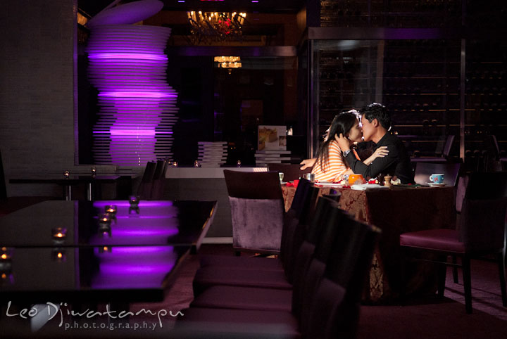 A girl and his fiancé kissing by the dinner table. Engagement proposal and pre wedding photo session at Restaurant Michel at Ritz-Carlton Hotel, Tysons Corner, Virginia, by Leo Dj Photography