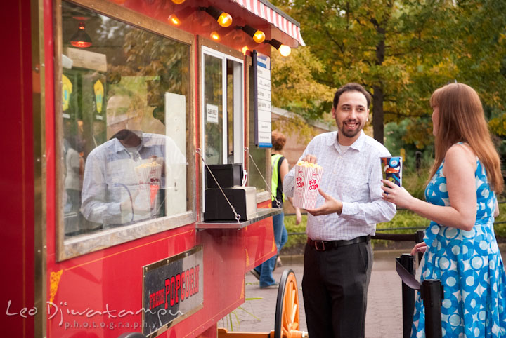 Engaged couple ordering pop-corn and soda drink at the stand. Washington DC National Zoo pre-wedding engagement session by Leo Dj Photography