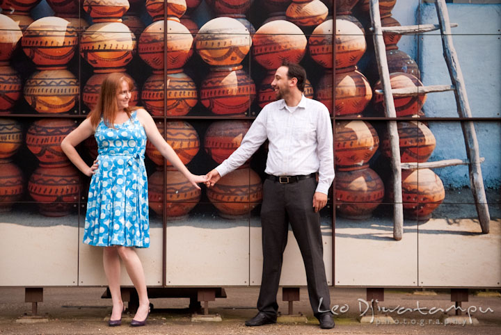 Engaged guy holding his fiancée's hand by a mural of African pottery. Washington DC National Zoo pre-wedding engagement session by Leo Dj Photography