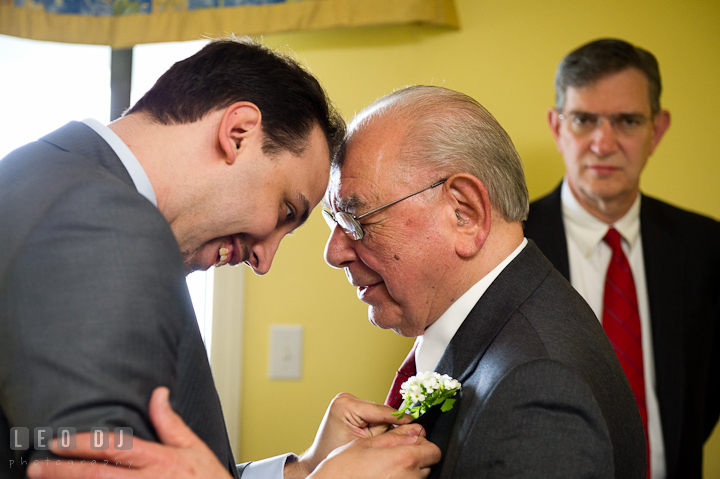 Groom putting boutonniere on grandfather's jacket. Harbourtowne Golf Resort wedding photos at St. Michaels, Eastern Shore, Maryland by photographers of Leo Dj Photography.