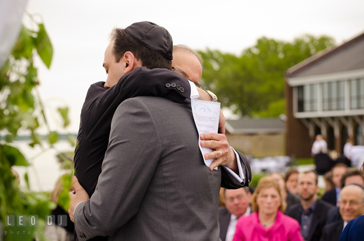 Father of Groom hugged son during ceremony. Harbourtowne Golf Resort wedding photos at St. Michaels, Eastern Shore, Maryland by photographers of Leo Dj Photography.