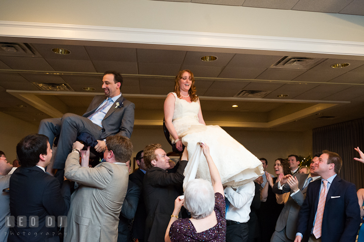 The Hora dance and the Bride and Groom sit on chairs lifted up in the air. Harbourtowne Golf Resort wedding photos at St. Michaels, Eastern Shore, Maryland by photographers of Leo Dj Photography.