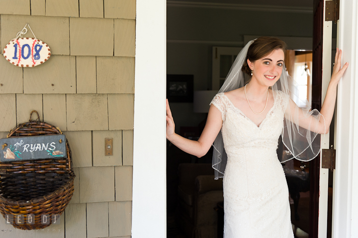 Bride posing and smiling in front of the house door. Saint John the Evangelist church wedding ceremony photos at Severna Park, Maryland by photographers of Leo Dj Photography. http://leodjphoto.com