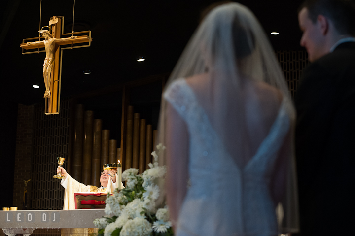 Priest blessing the bread and wine. Saint John the Evangelist church wedding ceremony photos at Severna Park, Maryland by photographers of Leo Dj Photography. http://leodjphoto.com