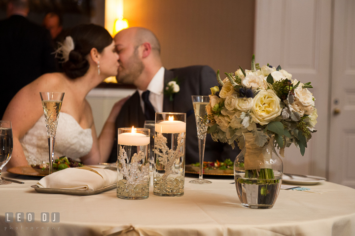 Bride and Groom kissing at sweetheart table behind Bride's floral bouquet by florist Monteray Farms. The Tidewater Inn wedding, Easton, Eastern Shore, Maryland, by wedding photographers of Leo Dj Photography. http://leodjphoto.com