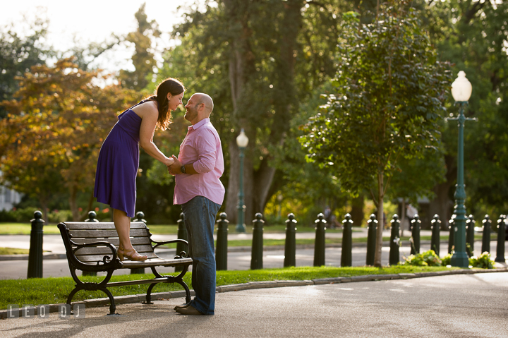 Engaged girl standing on a bench almost kissing her fiancé by the Capitol Hill. Washington DC pre-wedding engagement photo session, by wedding photographers of Leo Dj Photography. http://leodjphoto.com