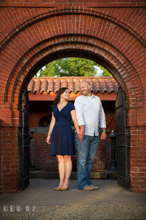 Engaged guy holding hands with his fiancée under a brick archway by the Capitol Hill. Washington DC pre-wedding engagement photo session, by wedding photographers of Leo Dj Photography. http://leodjphoto.com