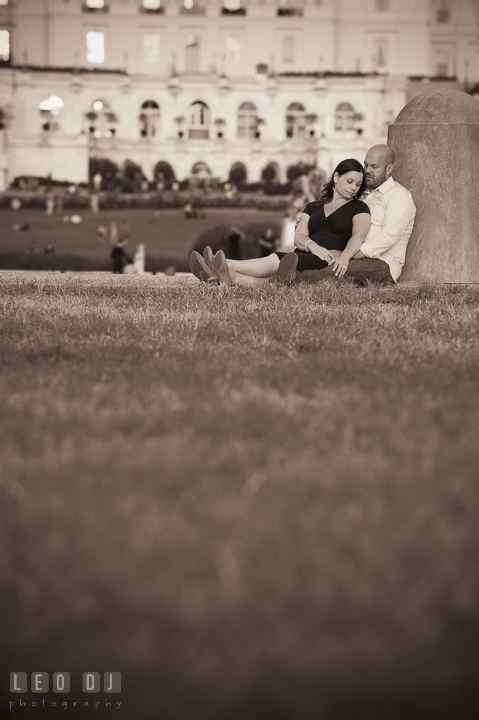 Engaged girl sitting on the lawn leaning against her fiancé by the Capitol Hill. Washington DC pre-wedding engagement photo session, by wedding photographers of Leo Dj Photography. http://leodjphoto.com