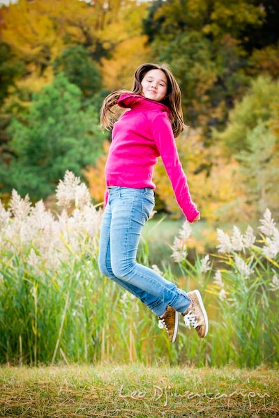 girl in pink sweater and jeans jumping, fall colored trees. Commercial comp card photograper Kent Island Annapolis MD Washington DC