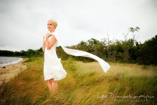 bride holding scarf blown by wind, looking at chesapeake bay beach. Annapolis Kent Island MD Modern Intimate Candid Posed Photojournalistic Style Wedding Photographer