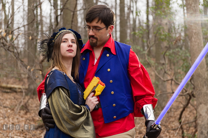 Engaged girl holding a nerf gun held close by her fiancé. Renaissance Costume Cosplay fun theme pre-wedding engagement photo session at Maryland, by wedding photographers of Leo Dj Photography. http://leodjphoto.com