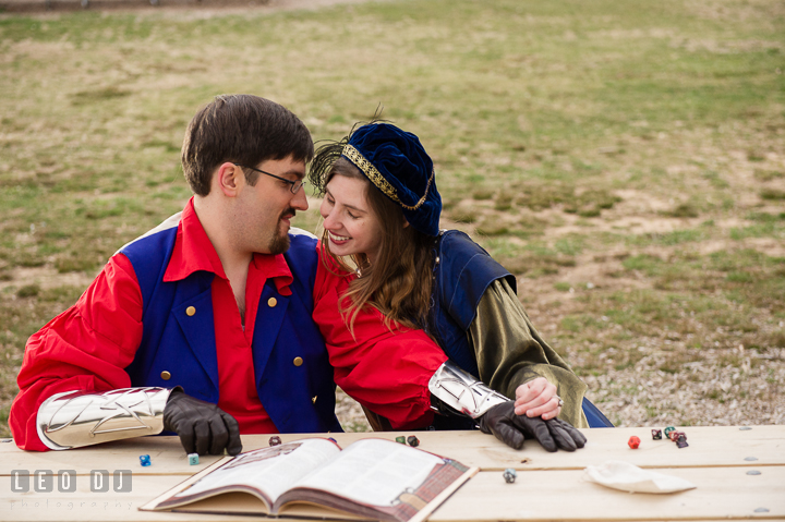 Engaged guy and his fiancée couple laughing and playing Dungeons and Dragons together. Renaissance Costume Cosplay fun theme pre-wedding engagement photo session at Maryland, by wedding photographers of Leo Dj Photography. http://leodjphoto.com