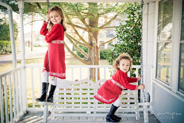 two girls playing on swing on porch. Candid children photographer St Michael Tilghman Island MD