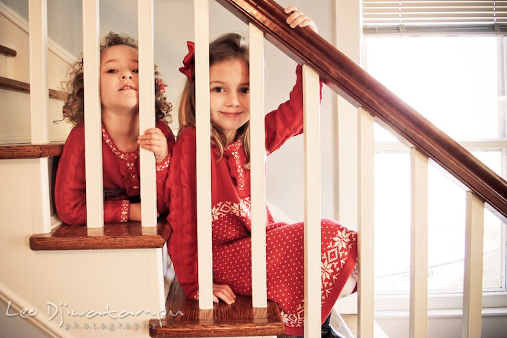 two sisters, posing behind stair railing, smiling. Candid children photographer St Michael Tilghman Island MD