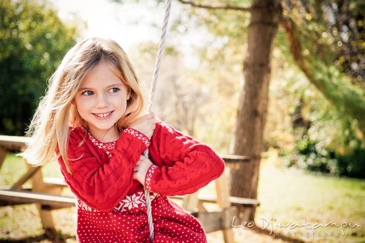 cute girl with blonde hair and blue eyes, playing swing. Candid children photographer St Michael Tilghman Island MD