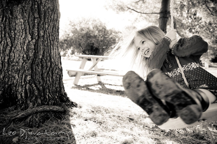 girl swinging under a tree in black and white. Candid children photographer St Michael Tilghman Island MD