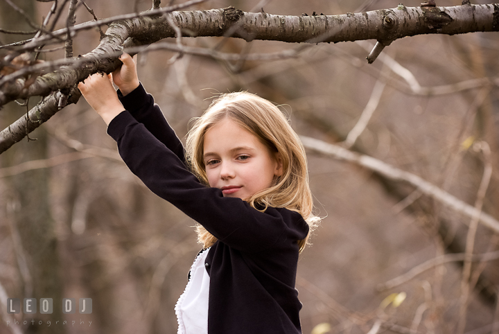 Girl hanging by a tree branch. Washington DC fun and candid children lifestyle photo session of Helena and Vivian by photographers of Leo Dj Photography.