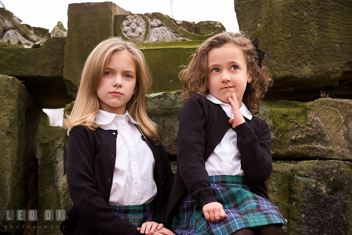 Two sisters posing by stone ruins. Washington DC fun and candid children lifestyle photo session of Helena and Vivian by photographers of Leo Dj Photography.