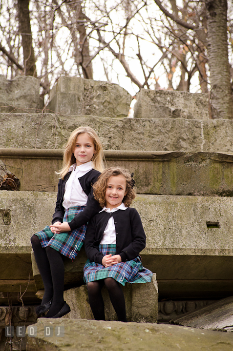 Two sisters sitting on building stone ruins. Washington DC fun and candid children lifestyle photo session of Helena and Vivian by photographers of Leo Dj Photography.