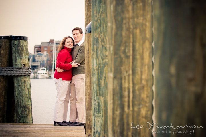 Engaged couple holding each other, on dock, pier. Urban city theme engagement session photographer Annapolis MD