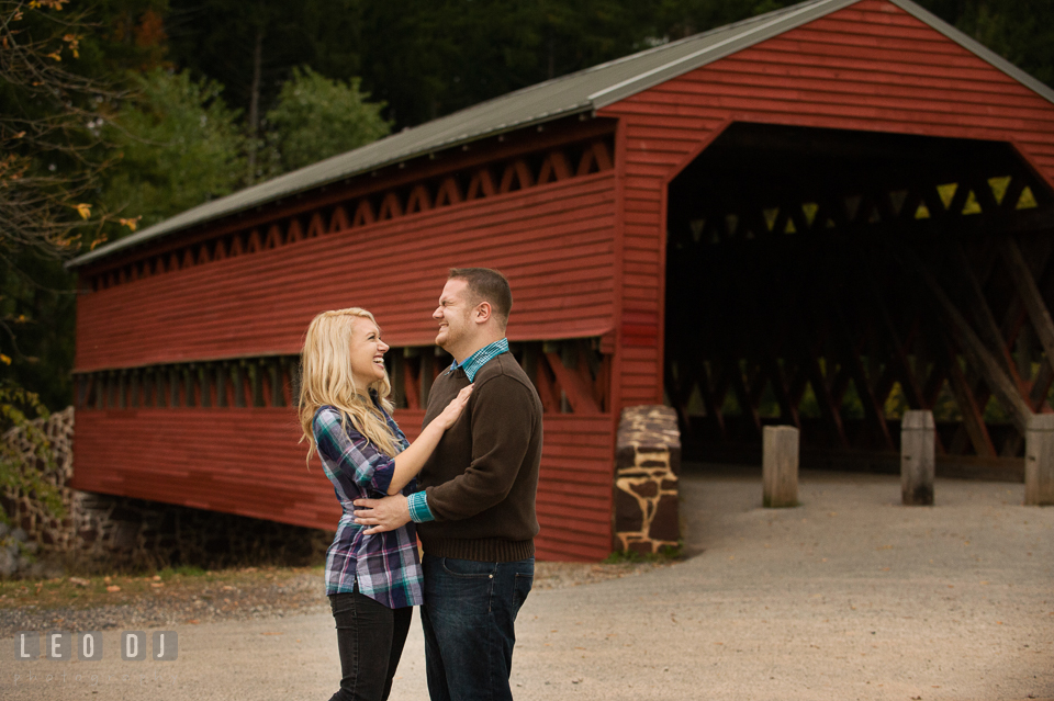 Engaged girl and her fiance embracing together and laughing by the Sachs Covered Bridge. Gettysburg PA pre-wedding engagement photo session, by wedding photographers of Leo Dj Photography. http://leodjphoto.com