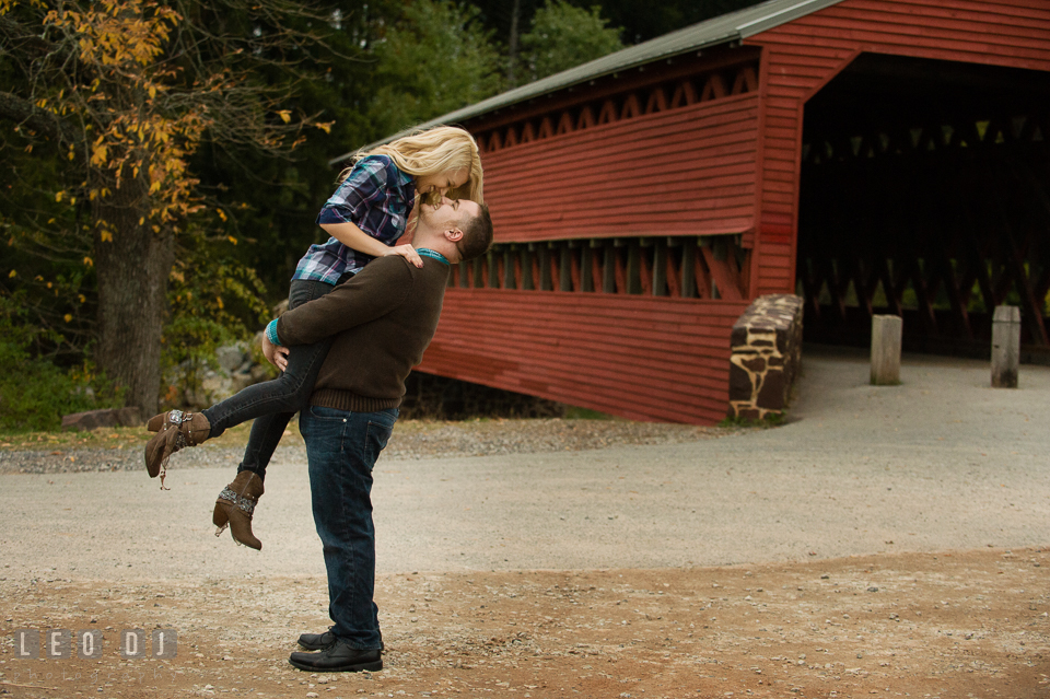 Engaged man lift up his fiancee laughing and almost kissed by the Sachs Covered Bridge. Gettysburg PA pre-wedding engagement photo session, by wedding photographers of Leo Dj Photography. http://leodjphoto.com