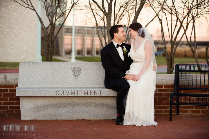 Bride sitting on lap of Groom whom sitting on the bench with Commitment inscription at the USNA. Historic Inns of Annapolis, Governor Calvert House wedding Maryland, by wedding photographers of Leo Dj Photography. http://leodjphoto.com