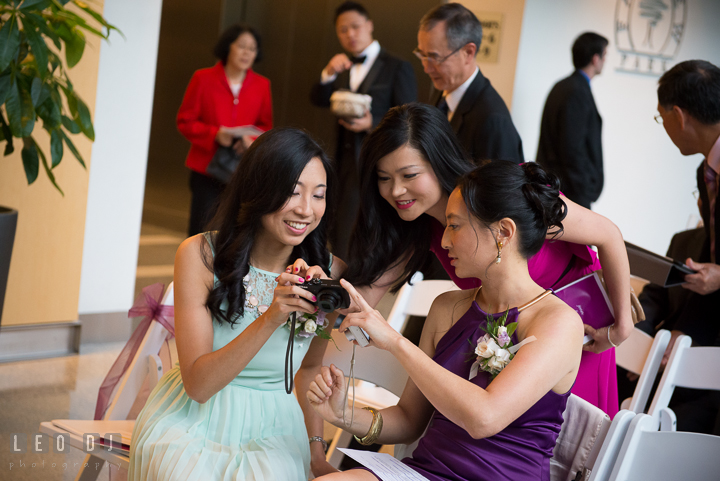 Groom's sisters and sister-in-law looking at photo result on camera. Falls Church Virginia 2941 Restaurant wedding ceremony photo, by wedding photographers of Leo Dj Photography. http://leodjphoto.com