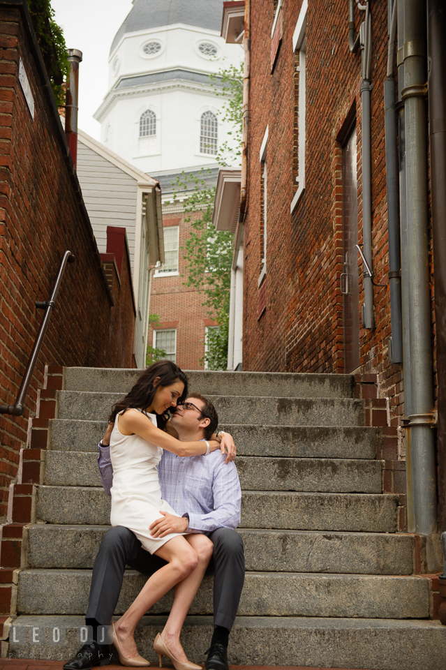 Engaged girl sitting on fiance's lap and snuggling. Annapolis Eastern Shore Maryland pre-wedding engagement photo session at downtown, by wedding photographers of Leo Dj Photography. http://leodjphoto.com