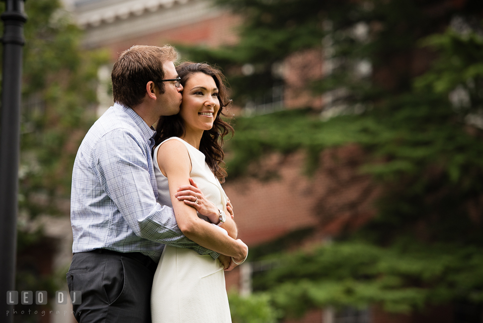 Engaged girl hugged and kissed by fiancé. Annapolis Eastern Shore Maryland pre-wedding engagement photo session at downtown, by wedding photographers of Leo Dj Photography. http://leodjphoto.com