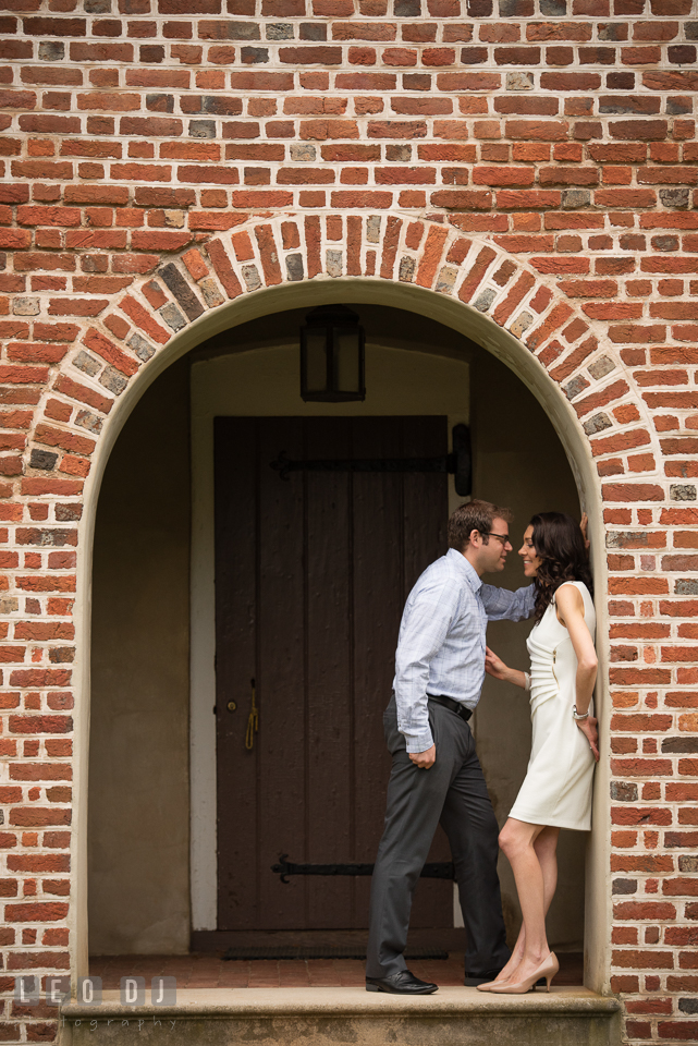 Loving engaged couple under a brick arch. Annapolis Eastern Shore Maryland pre-wedding engagement photo session at downtown, by wedding photographers of Leo Dj Photography. http://leodjphoto.com