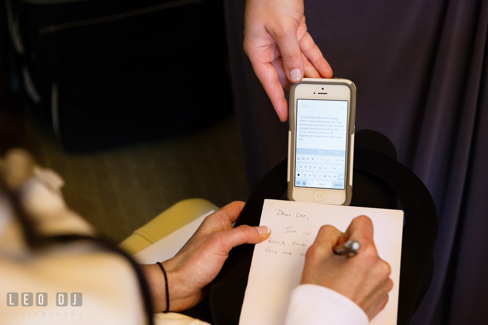 Bride writing a letter to Groom copying her draft from her iPhone. Loews Annapolis Hotel Maryland wedding, by wedding photographers of Leo Dj Photography. http://leodjphoto.com