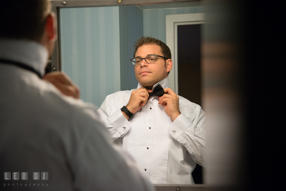 Groom looking in the mirror fixing his bow tie. Loews Annapolis Hotel Maryland wedding, by wedding photographers of Leo Dj Photography. http://leodjphoto.com