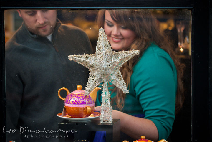 Engaged girl and her fiance browsing Christmas ornament and tea pot. Pre-wedding or engagement photo session at Annapolis city harbor, Maryland, Eastern Shore, by wedding photographers of Leo Dj Photography.