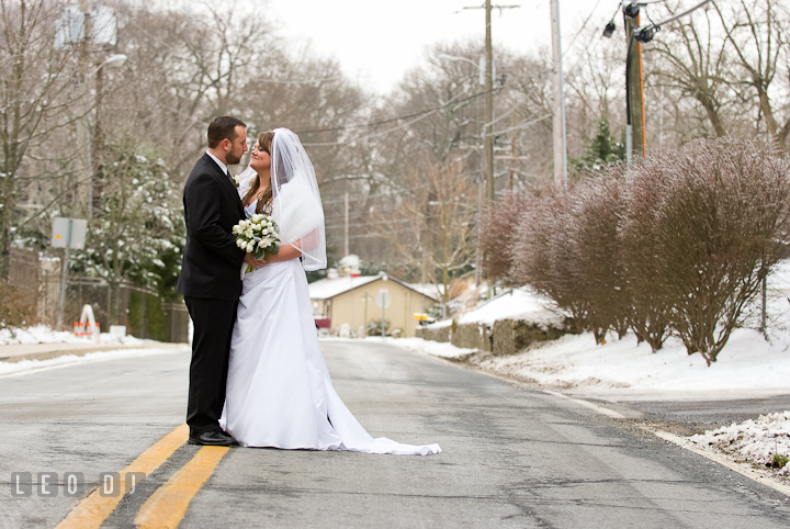 Bride and Groom cuddling in a wintry backdrop town. The Ballroom at The Chesapeake Inn wedding ceremony photos, Chesapeake City, Maryland by photographers of Leo Dj Photography.