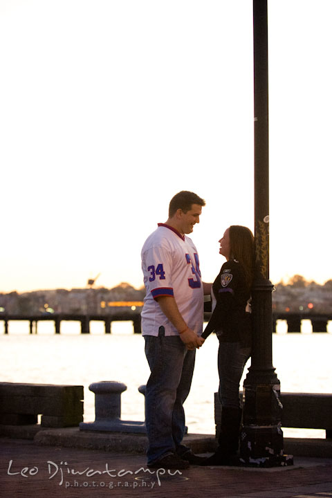 Engaged couple looking at each other by the pier. Fells Point Baltimore Maryland pre-wedding engagement photo session with their dog pet by wedding photographers of Leo Dj Photography