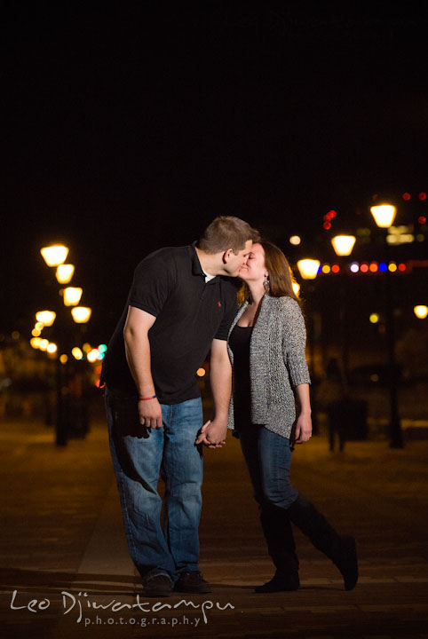 Engaged guy and girl kissing with the city lights in the background. Fells Point Baltimore Maryland pre-wedding engagement photo session with their dog pet by wedding photographers of Leo Dj Photography