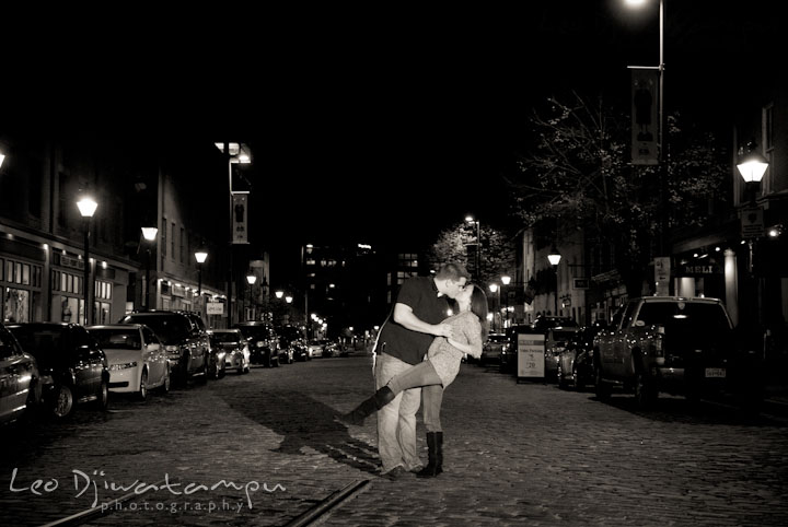 Engaged couple does the dip and kissed in the middle of the cobblestone street. Fells Point Baltimore Maryland pre-wedding engagement photo session with their dog pet by wedding photographers of Leo Dj Photography