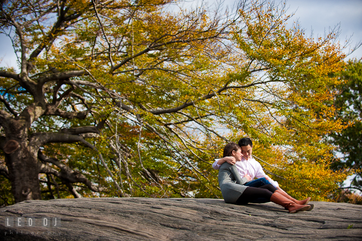 Engaged guy cuddling his fiancée on a huge rock at Central Park. Pre-wedding engagement photo session at New York City, NY, by wedding photographers of Leo Dj Photography. http://leodjphoto.com