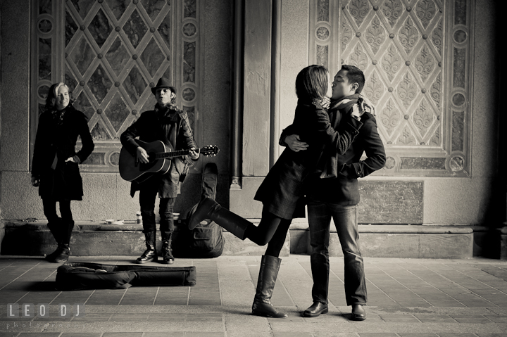 Engaged couple dancing and kissing to a street musician at Bethesda Terrace, Central Park. Pre-wedding engagement photo session at New York City, NY, by wedding photographers of Leo Dj Photography. http://leodjphoto.com