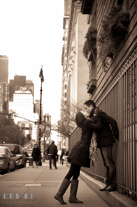 Engaged guy and girl kissing on the street sidewalk by the CNN building. Pre-wedding engagement photo session at New York City, NY, by wedding photographers of Leo Dj Photography. http://leodjphoto.com