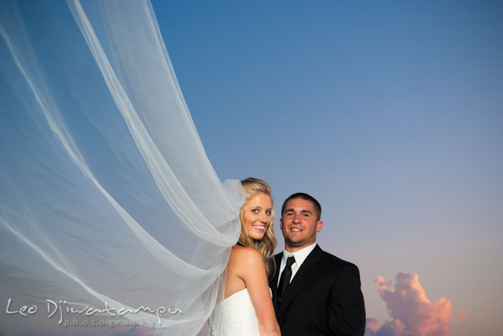 Bride with long veil and groom holding hands with sunset sky. Silver Swan Bayside Wedding Photos, Stevensville, Eastern Shore Maryland by wedding photographers of Leo Dj Photography