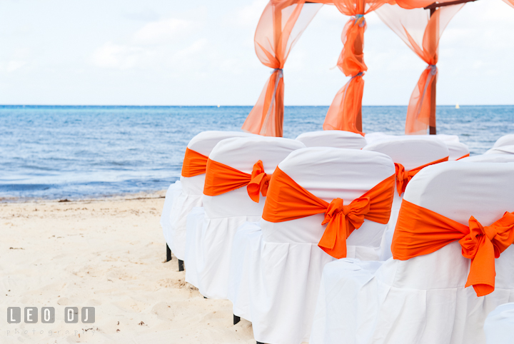 Ceremony chairs with orange ribbons overlooking at the blue sea. Cruise ship destination wedding ceremony photos, Hotel Melia Cozumel Mexico by photographers of Leo Dj Photography.