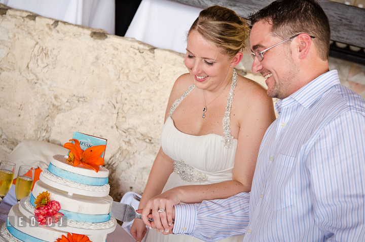 Bride and Groom smiling cutting the cake. Carnival Cruise ship destination wedding reception photos of Jessica and Chad, Cozumel Mexico by photographers of Leo Dj Photography.